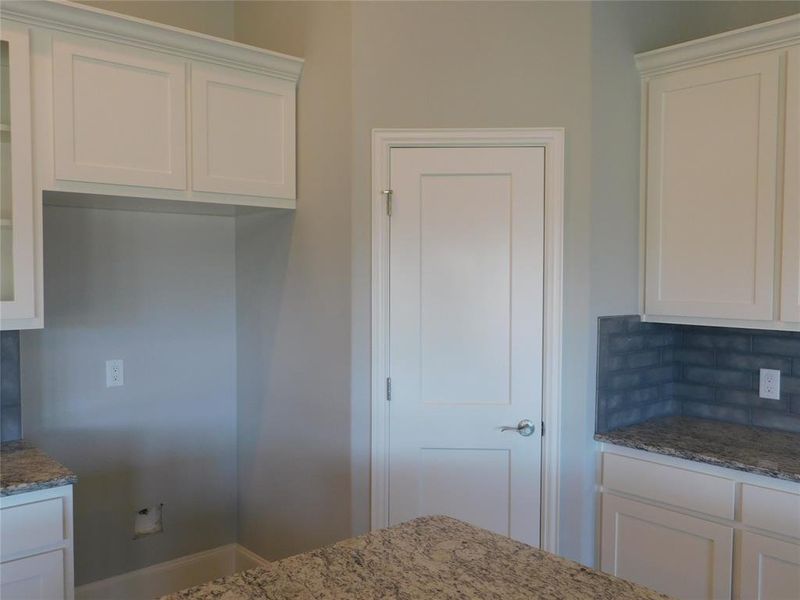 Kitchen featuring white cabinets, light stone countertops, and decorative backsplash