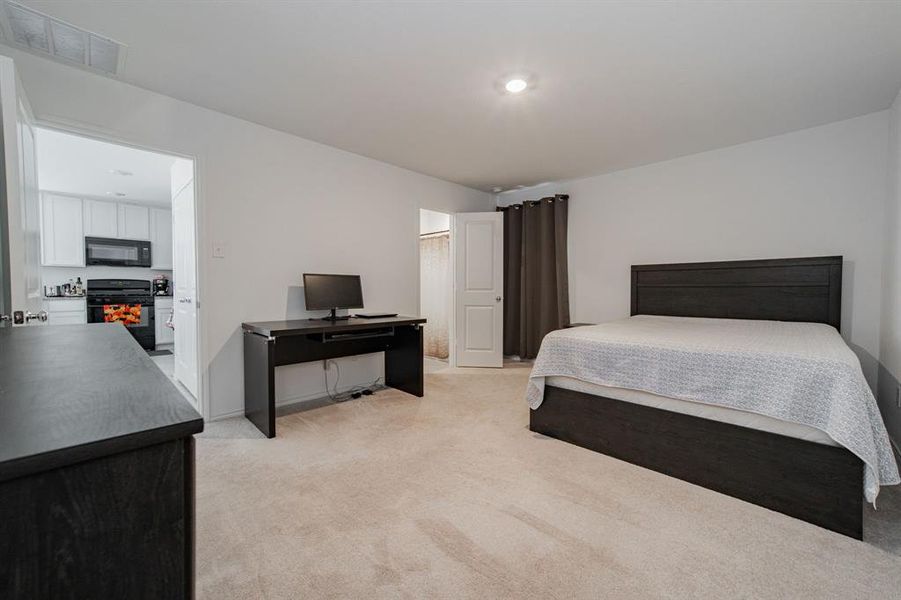 Bedroom featuring light carpet and a lit fireplace