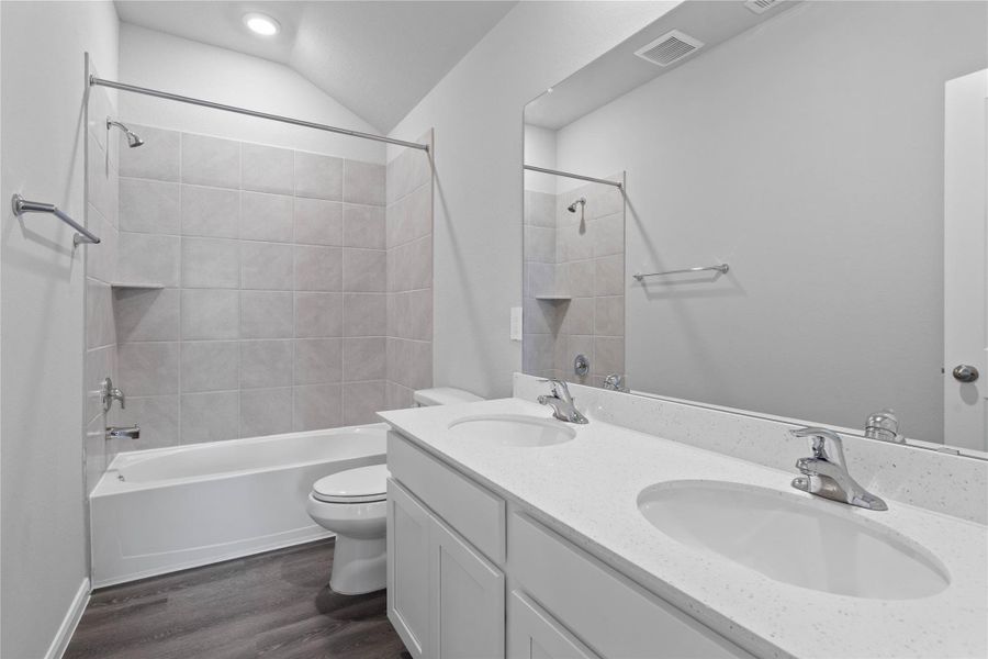 A streamlined secondary bathroom providing a functional tub/shower combination, double sinks, and modern fixtures, seamlessly blending practicality and style.