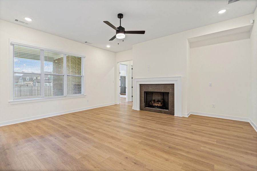 Spacious living area featuring wood-finish flooring, a contemporary ceiling fan, and recessed lighting Spacious living area featuring wood-finish flooring, a contemporary ceiling fan, and recessed lighting
