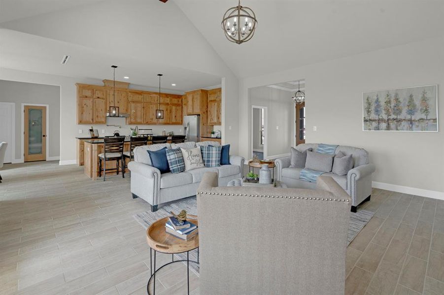 Living room featuring high vaulted ceiling, an inviting chandelier, and light wood-type flooring