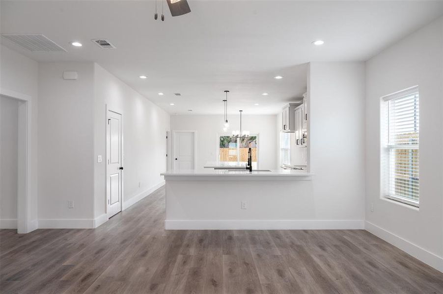 Unfurnished living room with sink, ceiling fan with notable chandelier, and hardwood / wood-style flooring