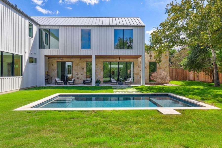 Rear view of property featuring a patio area, ceiling fan, stone siding, and a metal roof Rear view of property featuring a patio area, ceiling fan, stone siding, and a metal roof