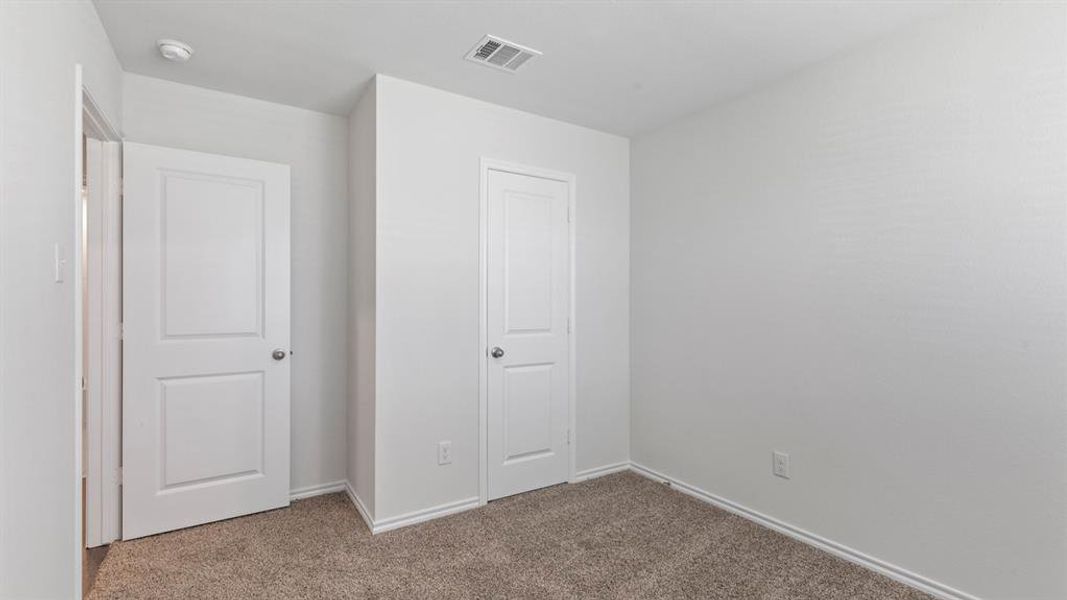 Interior room featuring light gray wall paint and textured carpet flooring