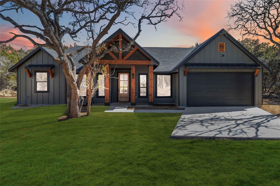 View of front facade with a garage and a lawn - green color added