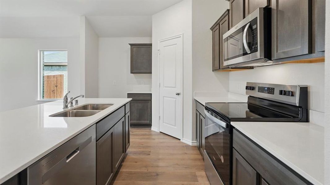 Kitchen featuring stainless steel appliances, dark wood finished floors, light stone countertops, and dark wood finish cabinetry