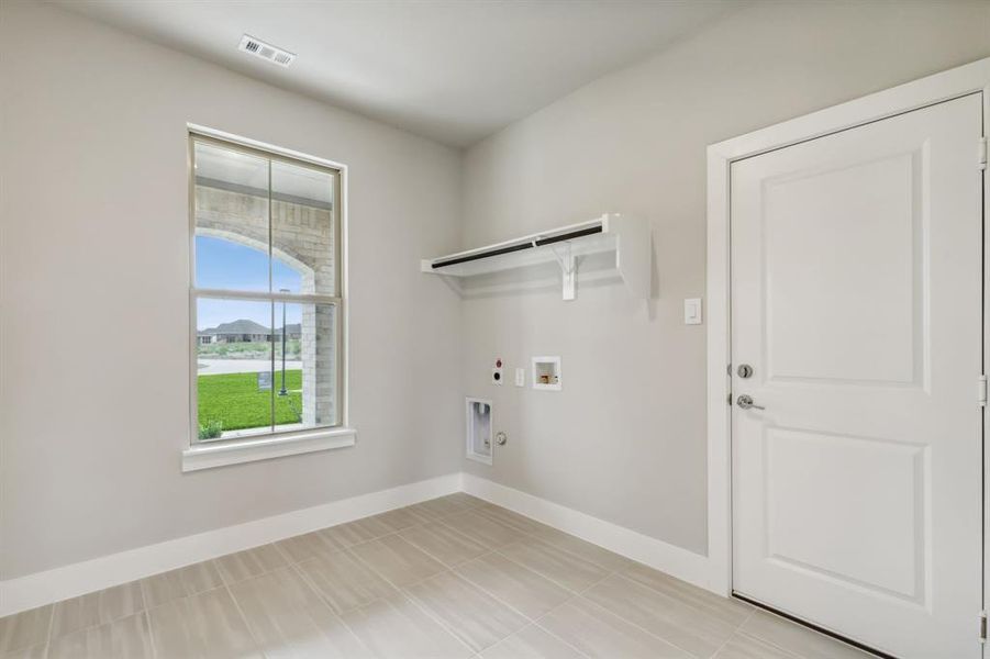 Washroom featuring hookup for a washing machine, hookup for a gas dryer, electric dryer hookup, and light tile patterned flooring