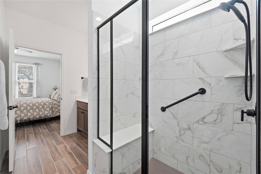 Bathroom with a marble finish shower, wood finish floors, ensuite bath, and vanity
