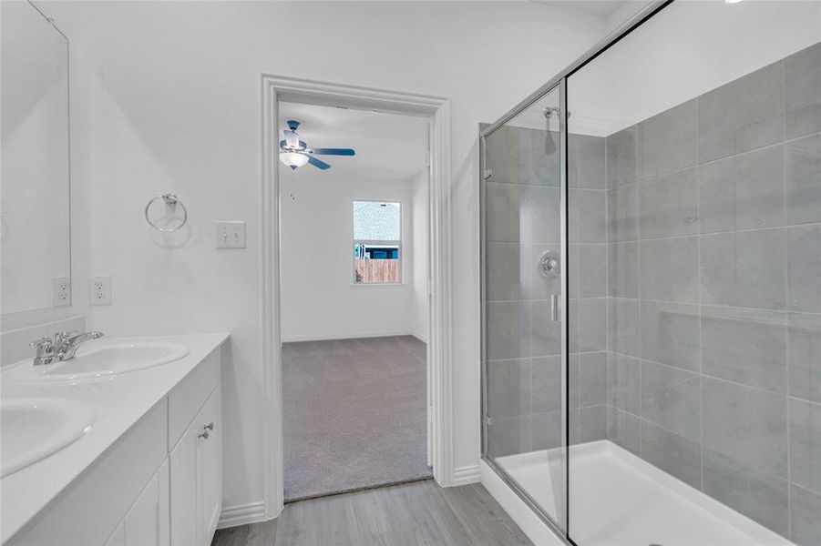 Bathroom featuring ceiling fan, vanity, hardwood / wood-style floors, and a shower with door