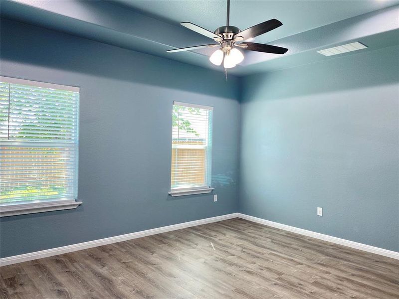 A quiet bedroom features wood flooring, tray ceiling, and natural light from two well-placed windows. A quiet bedroom features wood flooring, tray ceiling, and natural light from two well-placed windows.