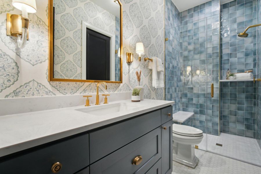 Bathroom with a shower stall, wallpapered walls, toilet, tile patterned floors, and vanity