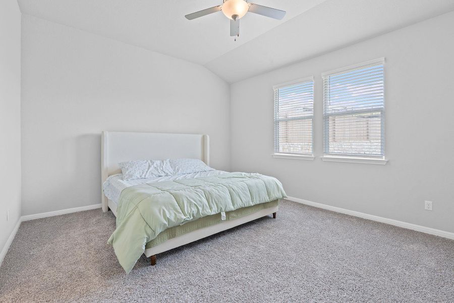 Carpeted bedroom with baseboards, a ceiling fan, and vaulted ceiling Carpeted bedroom with baseboards, a ceiling fan, and vaulted ceiling