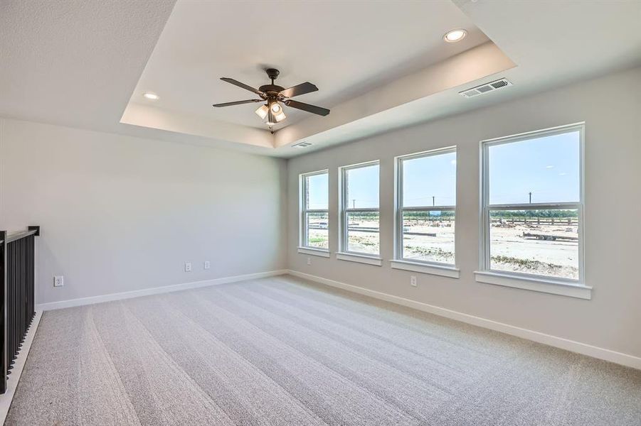 Empty room with a raised ceiling, a ceiling fan, light carpet, recessed lighting, and baseboards Empty room with a raised ceiling, a ceiling fan, light carpet, recessed lighting, and baseboards