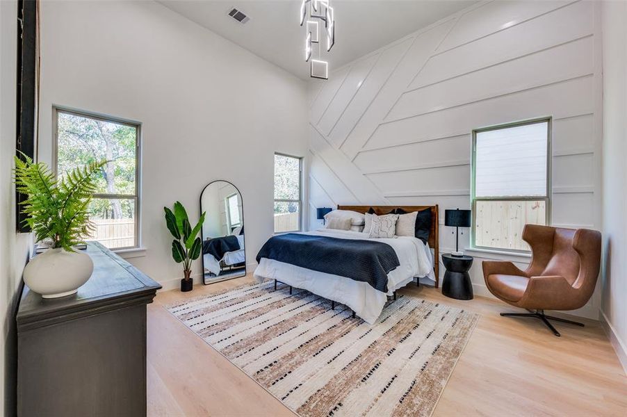 Bedroom featuring a towering ceiling and light hardwood / wood-style flooring