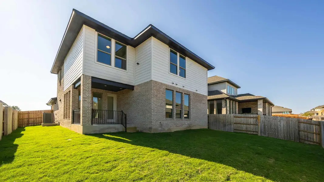 Back of property featuring a fenced backyard, brick siding, and a patio area