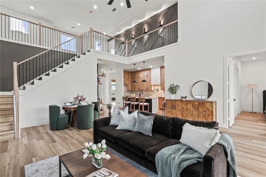 Expansive living room featuring high ceilings, wood-finish flooring, and a contemporary staircase with black metal balusters