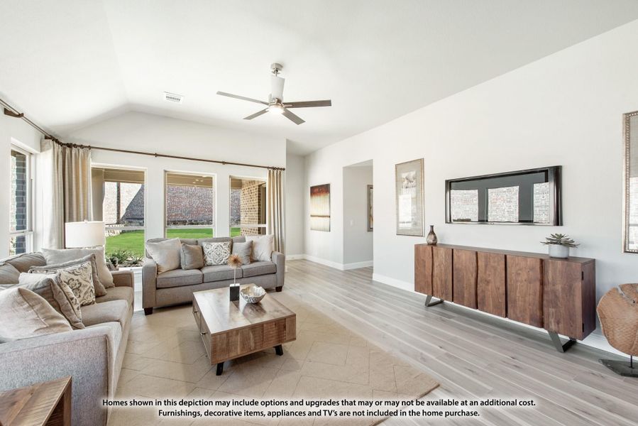 Living room with vaulted ceiling, ceiling fan, gray sofas, wood coffee table, and large windows with natural light. Living room with vaulted ceiling, ceiling fan, gray sofas, wood coffee table, and large windows with natural light.