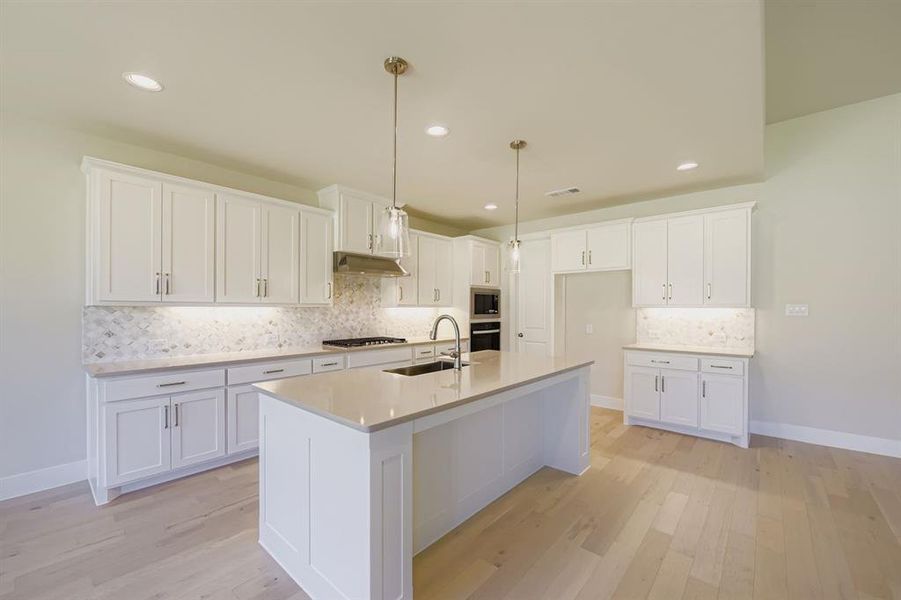 Kitchen featuring tasteful backsplash, white cabinetry, decorative light fixtures, light wood-style flooring, and recessed lighting