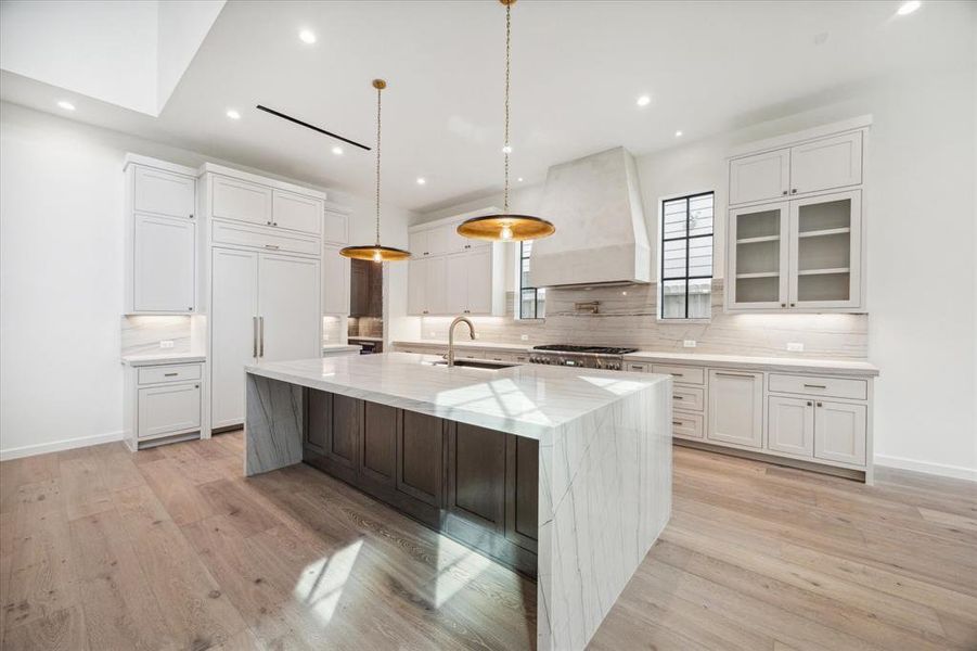 Gourmet kitchen equipped with high-end Thermador appliances, custom cabinetry, and a professional-grade stove. Elegant pendant lighting highlights the central island, ideal for meal preparation and entertaining.