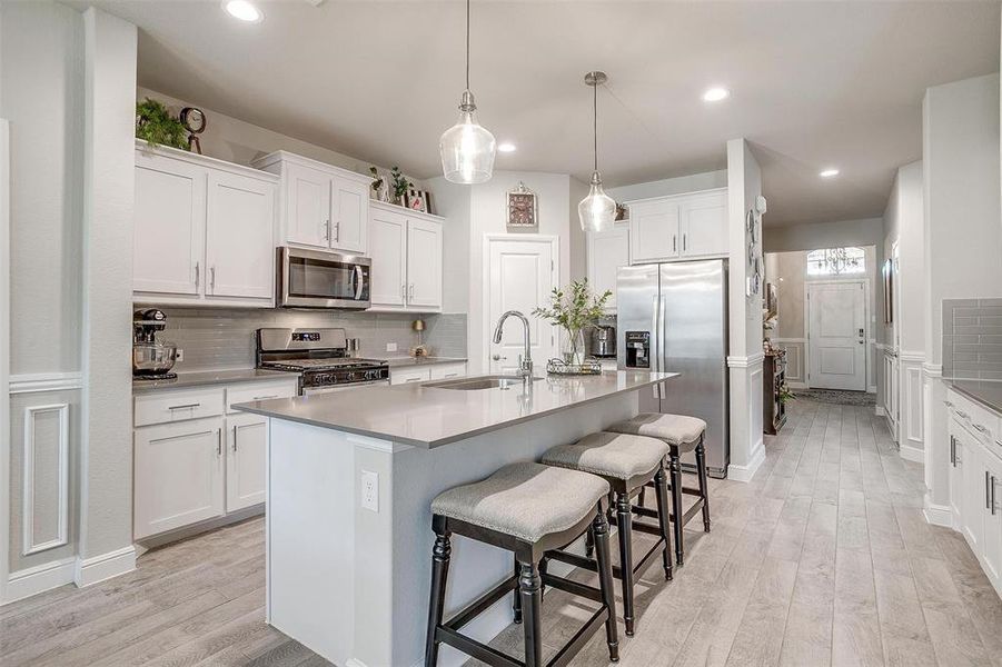 Kitchen featuring a breakfast bar, light wood-style floors, stainless steel appliances, and a sink