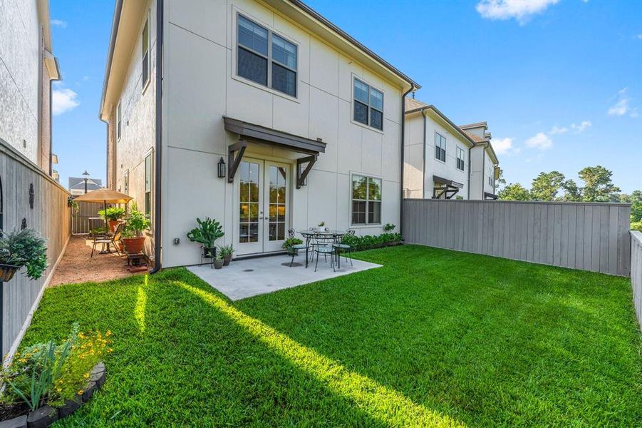 The spacious back yard features a patio and lush green space.