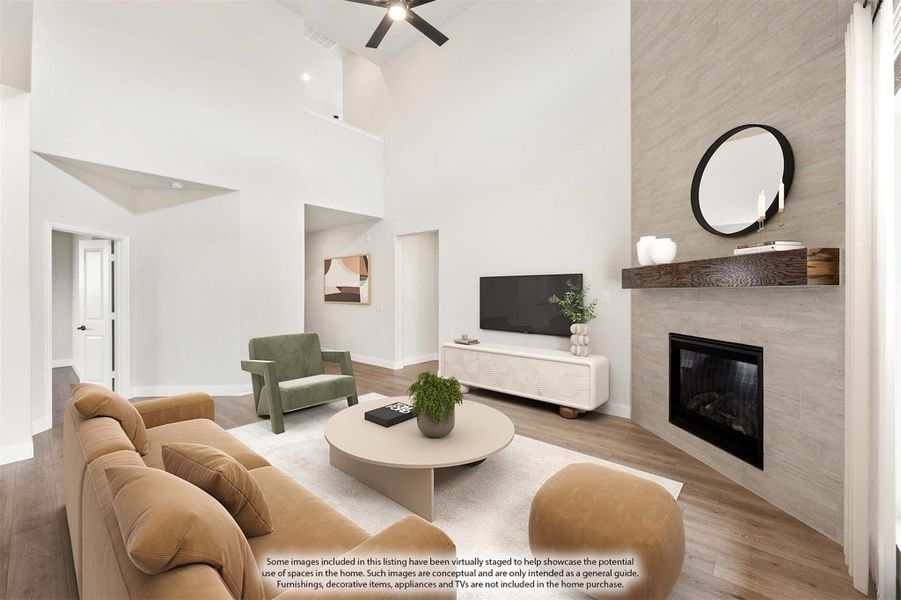Living room with high vaulted ceiling, tile fireplace, ceiling fan, and hardwood floors Living room with high vaulted ceiling, tile fireplace, ceiling fan, and hardwood floors