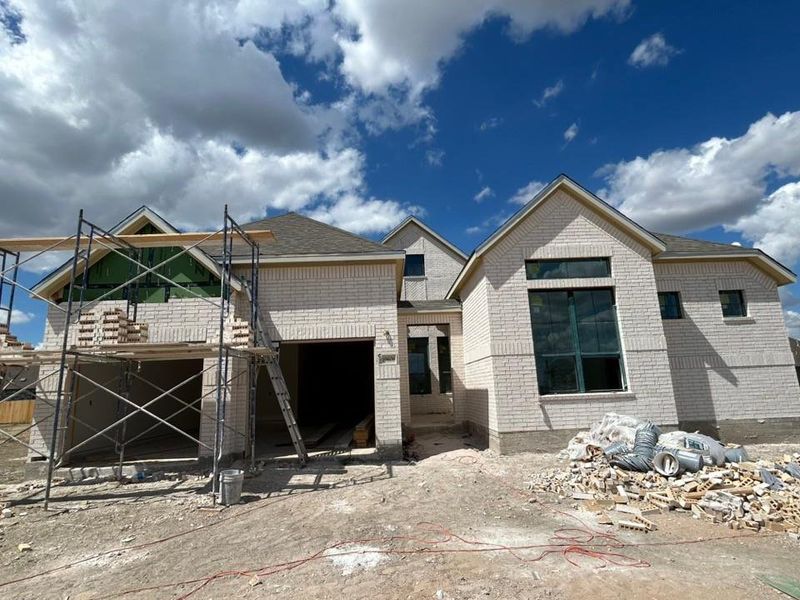 Property under construction featuring brick siding, a shingled roof, and a patio Property under construction featuring brick siding, a shingled roof, and a patio