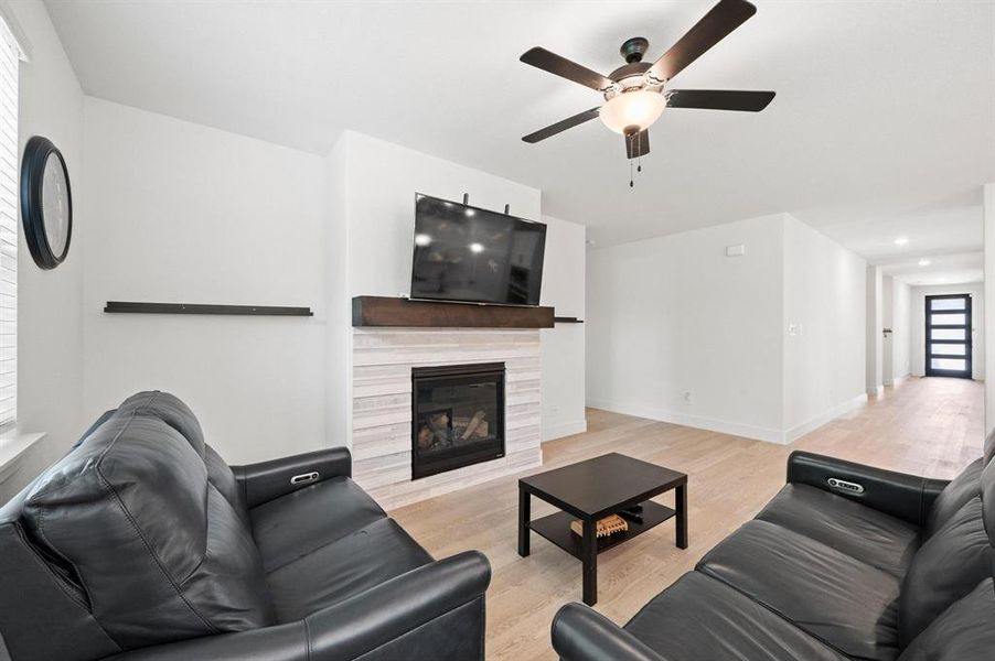 Living area featuring a fireplace with a light-toned tile surround and a dark wood-finish mantel Living area featuring a fireplace with a light-toned tile surround and a dark wood-finish mantel