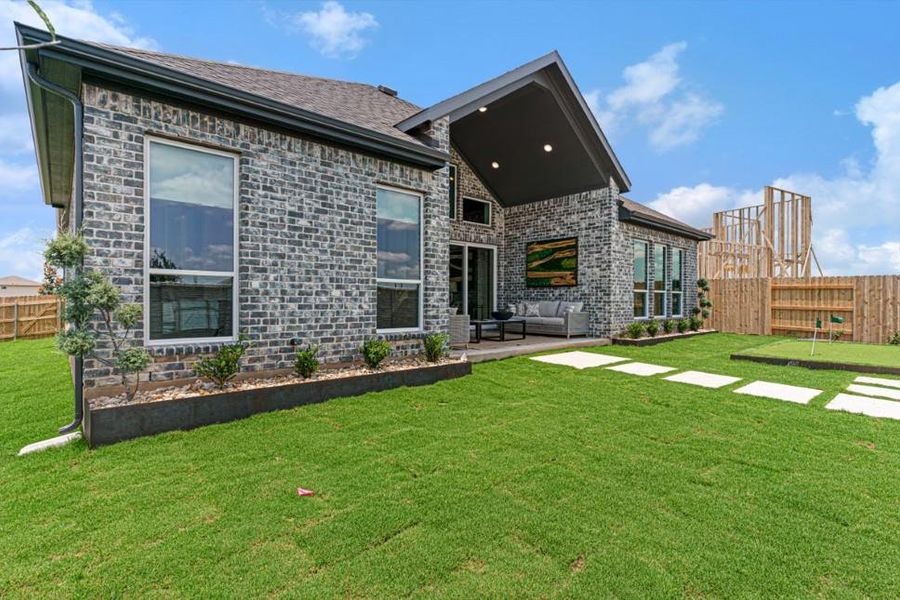 Rear view of house featuring outdoor lounge area, a putting green, and stone siding