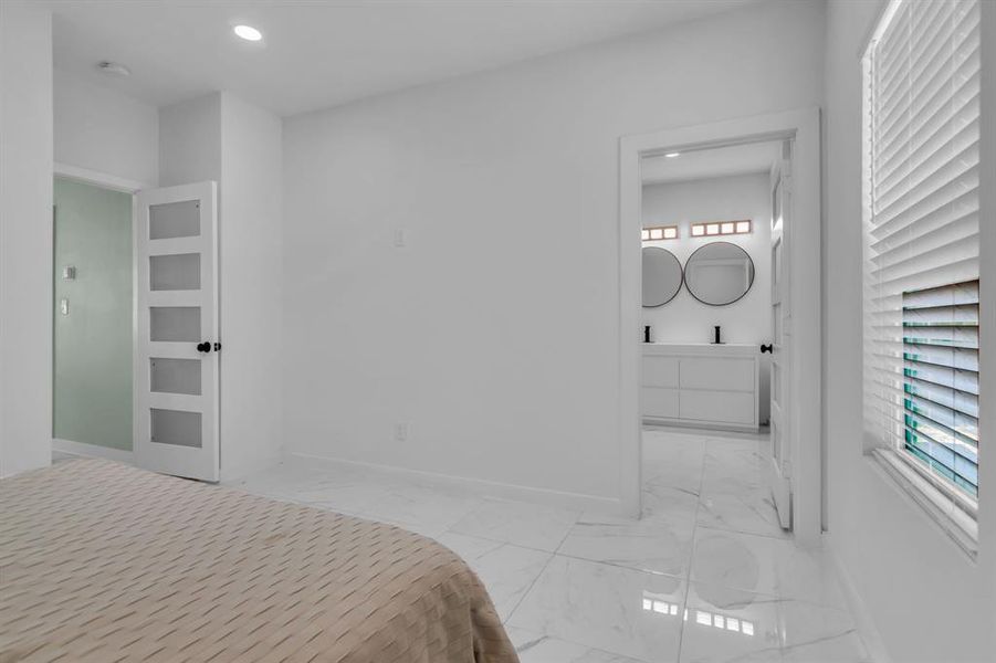 Bedroom with light marble finish floors, connected bathroom, and recessed lighting Bedroom with light marble finish floors, connected bathroom, and recessed lighting