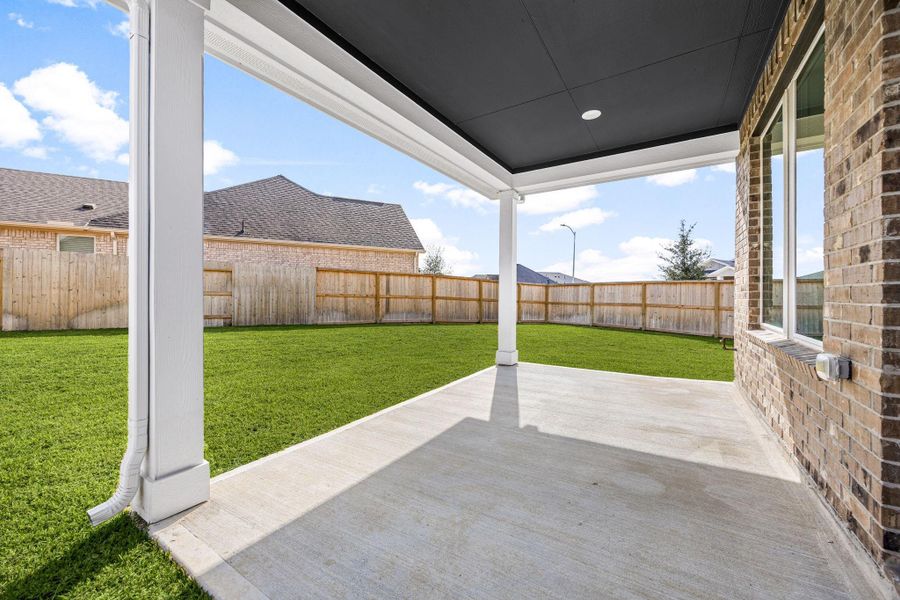 Step outside to a spacious, covered concrete patio perfect for outdoor dining and relaxing. This inviting outdoor living space features crisp white support columns and seamlessly transitions to a fully enclosed private backyard with lush green lawn and a durable wood privacy fence, offering a secure and low-maintenance area for leisure and recreation. Step outside to a spacious, covered concrete patio perfect for outdoor dining and relaxing. This inviting outdoor living space features crisp white support columns and seamlessly transitions to a fully enclosed private backyard with lush green lawn and a durable wood privacy fence, offering a secure and low-maintenance area for leisure and recreation.