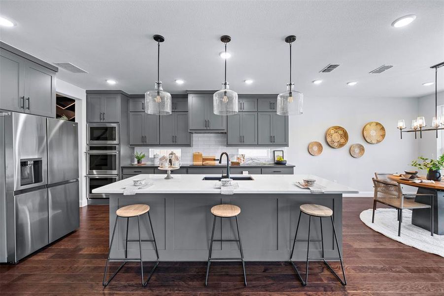 Kitchen featuring appliances with stainless steel finishes, a kitchen breakfast bar, gray cabinets, tasteful backsplash, and recessed lighting