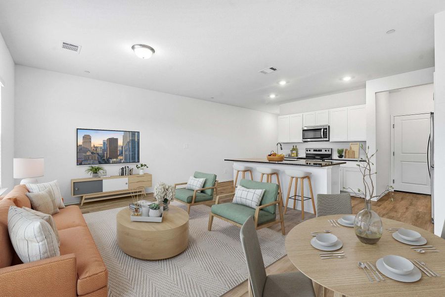 Open-concept living space with wood-finish flooring, white walls, and recessed lighting Open-concept living space with wood-finish flooring, white walls, and recessed lighting
