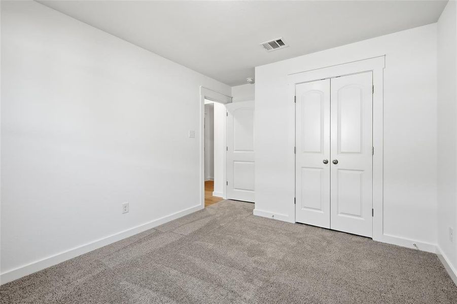 Unfurnished bedroom with light carpet and a closet