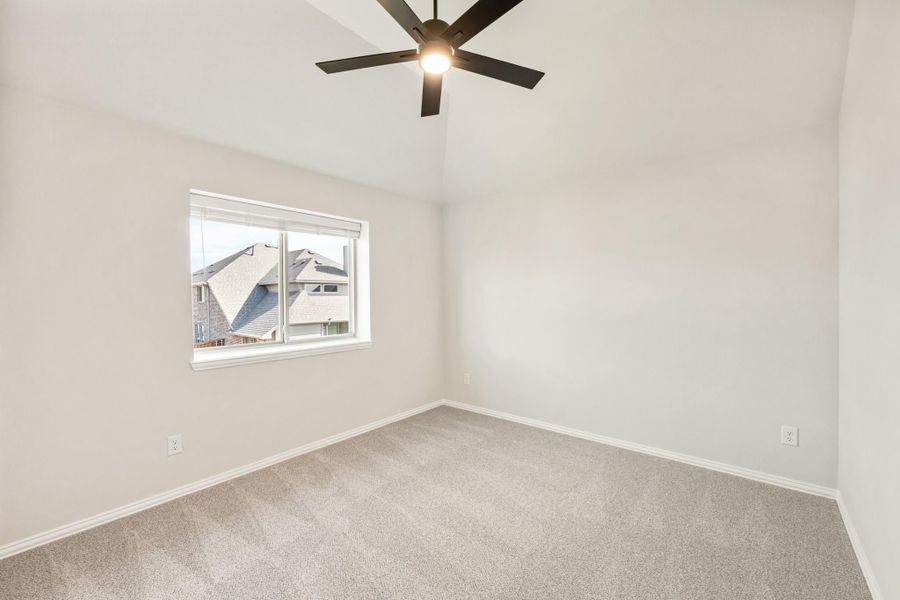 Empty bedroom with vaulted ceiling, ceiling fan, carpet flooring, and single window