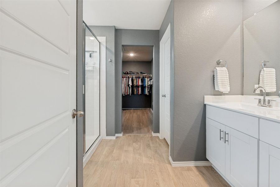A sleek vanity with ample storage complements the adjacent walk-in shower and closet access.