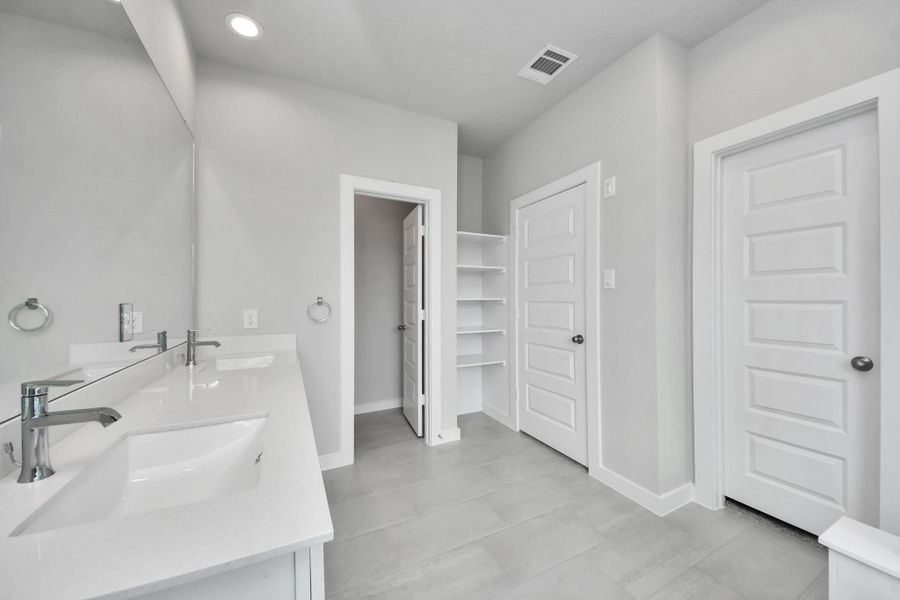 Elevate your daily routine at the elegant vanity, now equipped with double sinks, light countertops, modern hardware, and beautiful recessed lights. Sample photo of completed home with similar floor plan. Actual colors and selections may vary.