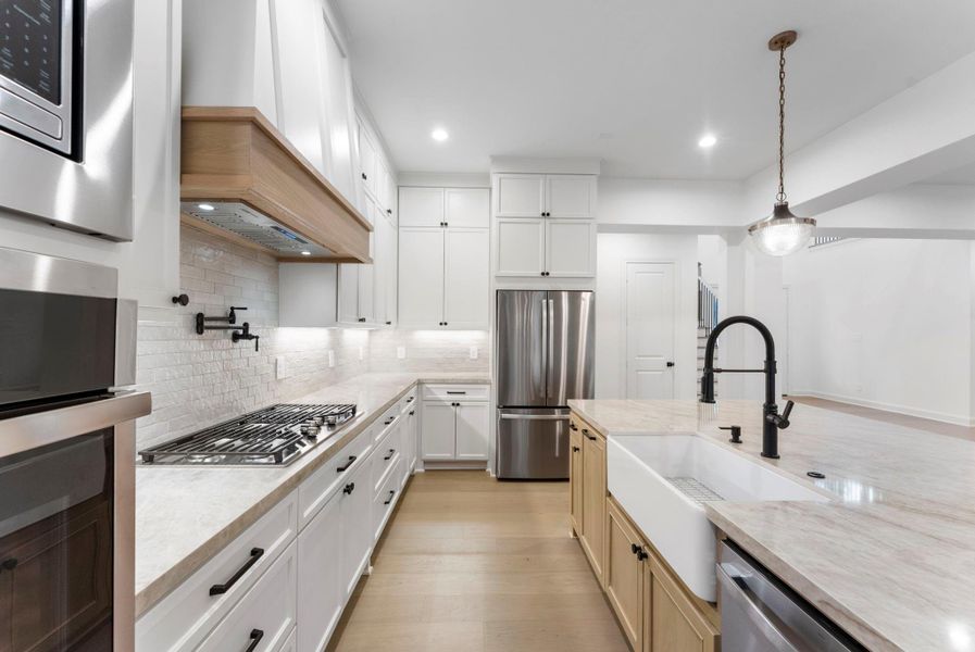 The gas cooktop, pot filler, and farmhouse style sink make this kitchen more than complete!