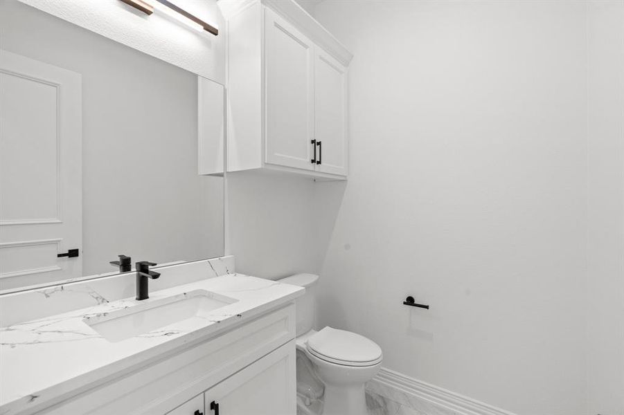 Half bath featuring vanity and marble finish flooring Half bath featuring vanity and marble finish flooring