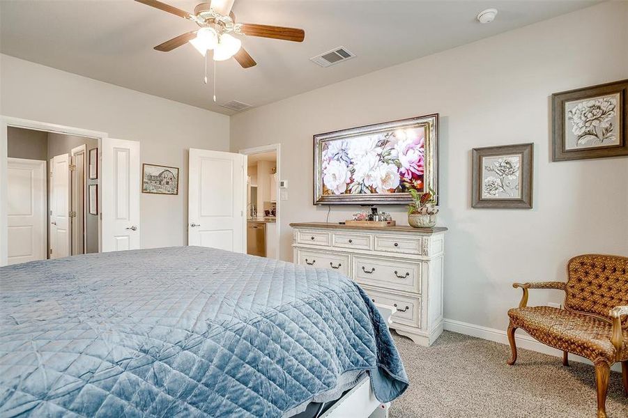 Bedroom with a ceiling fan, light colored carpet, visible vents, and baseboards