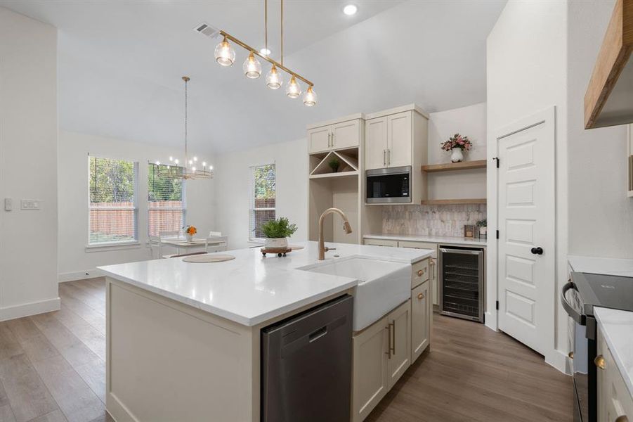 Kitchen featuring appliances with stainless steel finishes, decorative backsplash, beverage cooler, pendant lighting, and light stone countertops Kitchen featuring appliances with stainless steel finishes, decorative backsplash, beverage cooler, pendant lighting, and light stone countertops