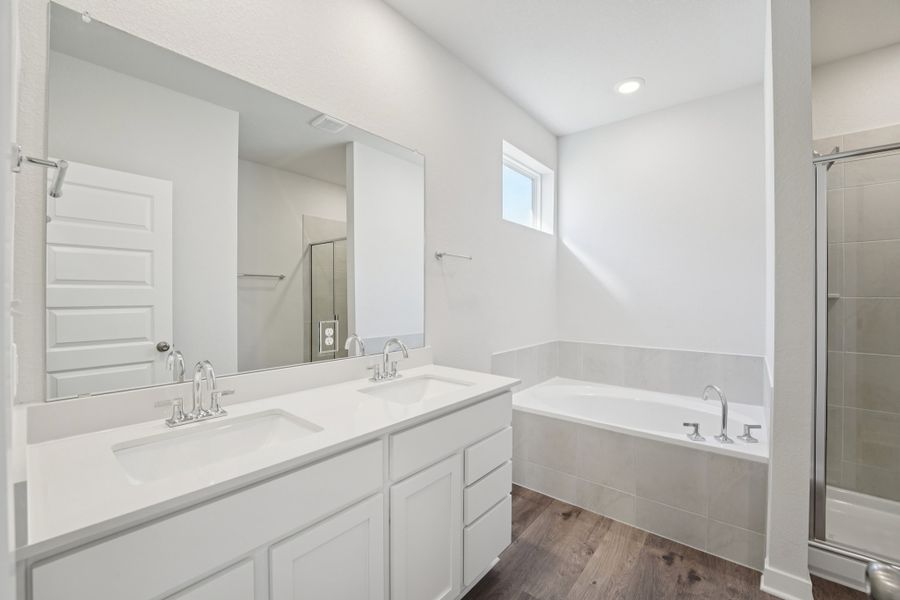 A bathroom with a tub sink and mirror.