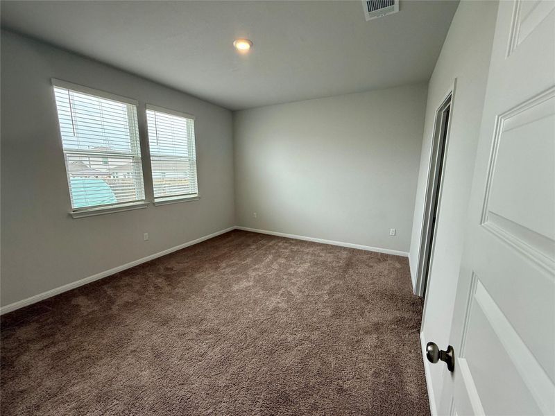Spacious room featuring neutral painted walls, brown carpeting, and two windows with blinds
