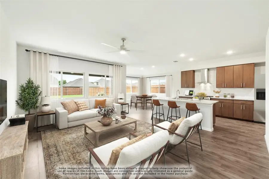 Open-concept living room and kitchen with hardwood floors, ceiling fan, and wood cabinets