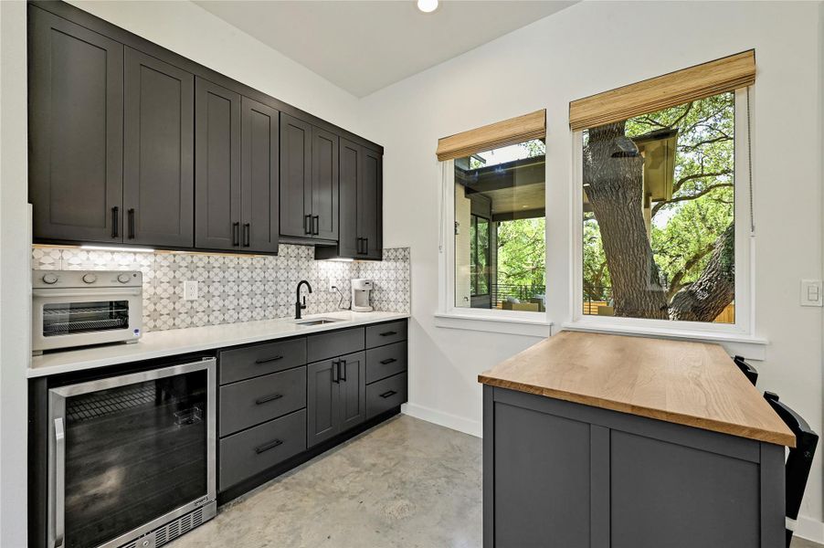 Casita wet bar with dark cabinetry, patterned tile backsplash, wine fridge, and custom butcher block island. Casita wet bar with dark cabinetry, patterned tile backsplash, wine fridge, and custom butcher block island.