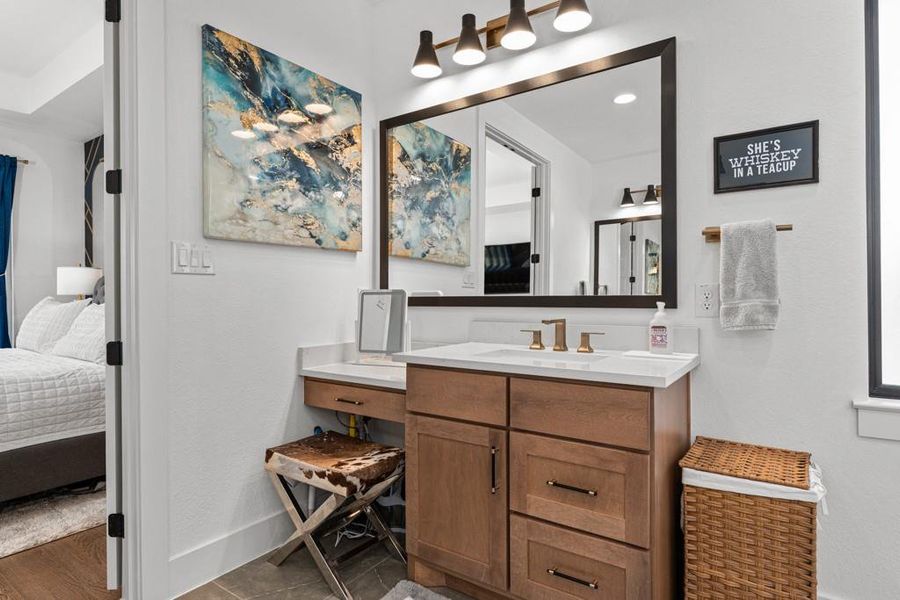 A well-appointed bathroom vanity with a makeup station opens directly to an inviting bedroom. A well-appointed bathroom vanity with a makeup station opens directly to an inviting bedroom.