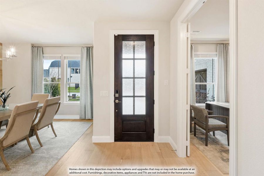 Entryway with dark wood glass-panel door, hardwood floors, and view into dining room and home office