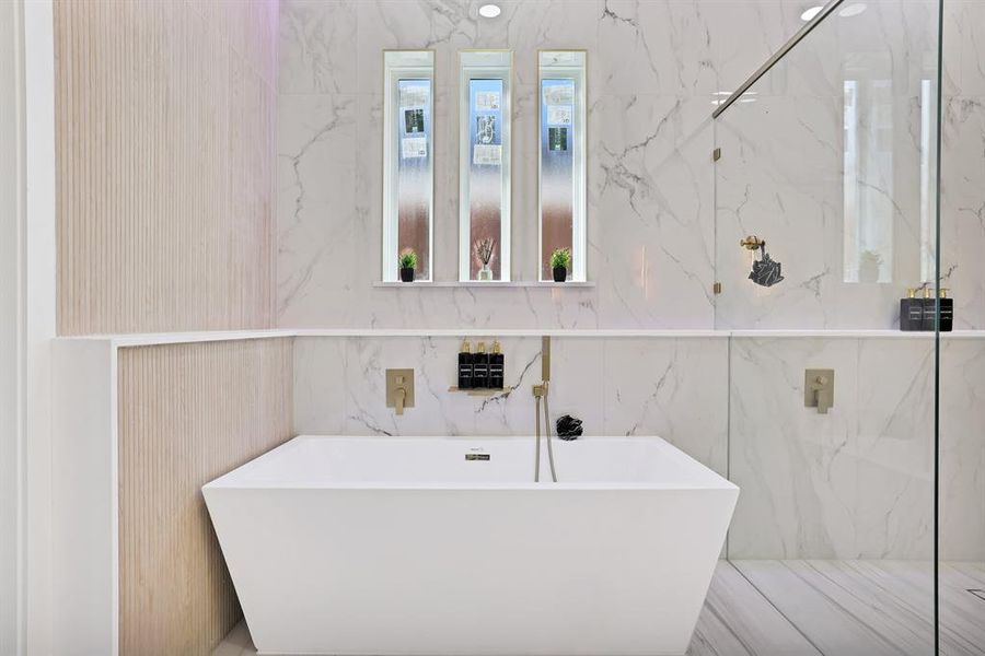 Bathroom featuring a washtub and tile walls