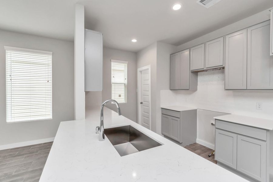 Culinary haven, featuring granite countertops, a tile backsplash, stainless steel appliances (to be installed), and 42” upper cabinets. Sample photo of completed home with similar floor plan. Actual colors and selections may vary.