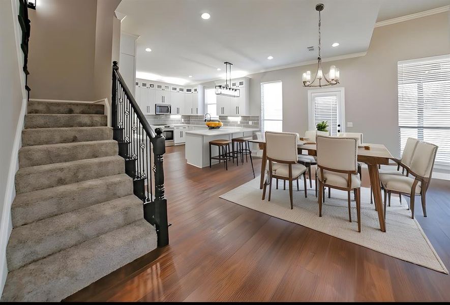 Dining room with stairs, recessed lighting, dark wood finished floors, crown molding, and a chandelier Dining room with stairs, recessed lighting, dark wood finished floors, crown molding, and a chandelier